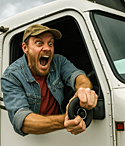A truck driver shouting out the window of his truck.